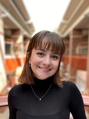 Smiling girl with shoulder length straight brown hair wearing a black turtle neck